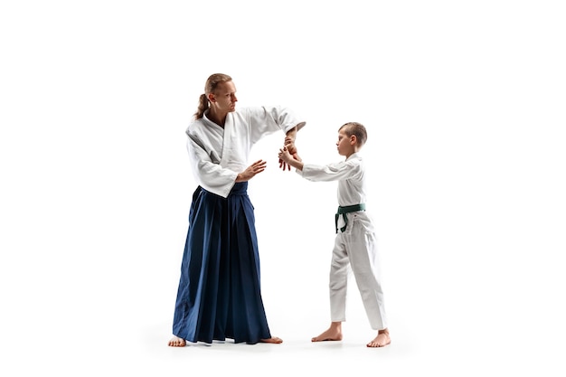 Uomo e ragazzo adolescente che combattono all'allenamento di Aikido nella scuola di arti marziali. Stile di vita sano e concetto di sport. Combattenti in kimono bianco sul muro bianco. Uomini di karate con facce concentrate in uniforme.