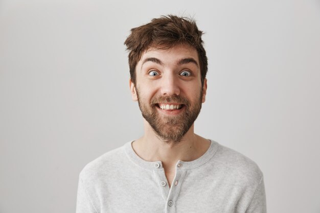 Uomo eccitato pazzo con i capelli scossi che sorridono ampiamente