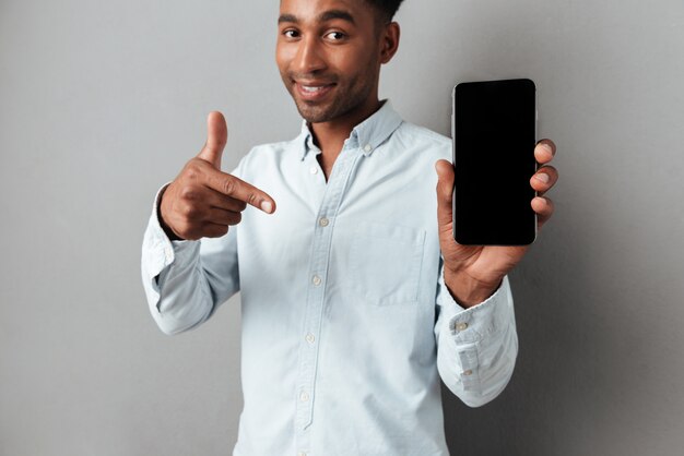 Uomo emozionante che indica barretta al telefono mobile dello schermo in bianco