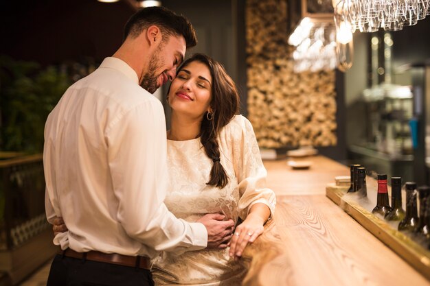 Uomo felice che abbraccia donna allegra al bancone del bar