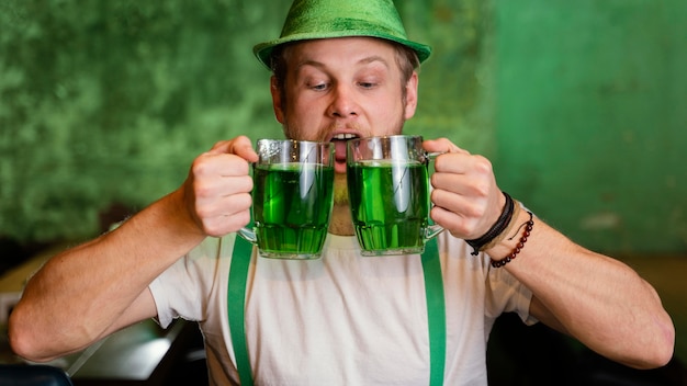 Uomo felice che celebra st. patrick's day con drink al bar