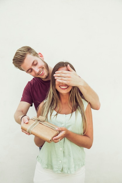 Uomo felice che chiude gli occhi della sua ragazza mentre dà il regalo a sorpresa