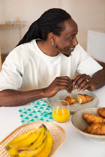 Uomo felice che mangia prima colazione con le banane