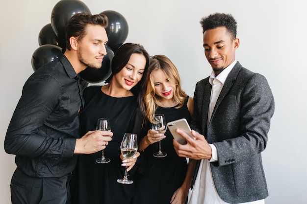 Uomo felice che mostra le ultime foto degli amici sul suo telefono durante la festa