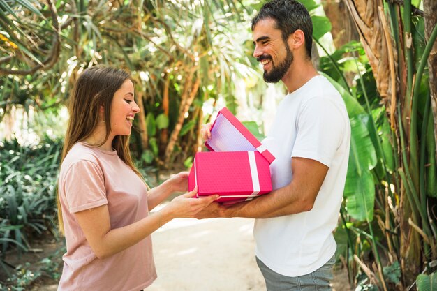 Uomo felice che mostra regalo alla sua ragazza nel parco