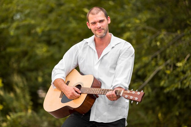 Uomo felice che suona la chitarra nella natura