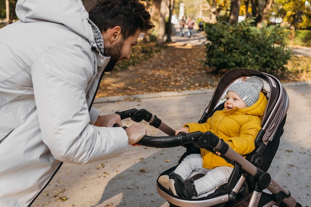 Uomo felice con il suo bambino all'aperto nel passeggino