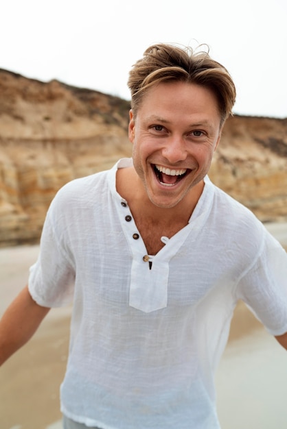 Uomo felice del tiro medio alla spiaggia?