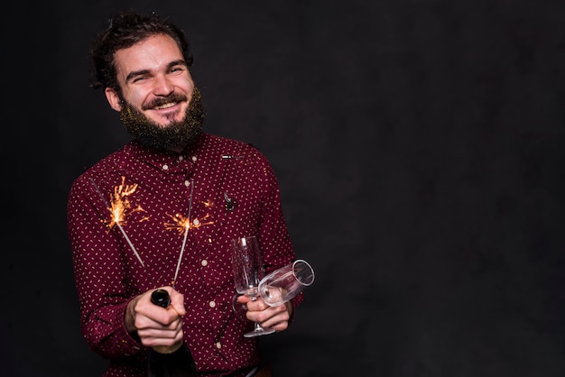 Uomo felice in piedi con gli occhiali e le stelle filanti