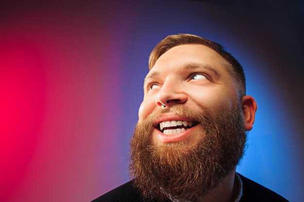 Uomo felice in piedi e sorridente isolato su sfondo rosa studio. Bellissimo ritratto maschile a mezzo busto. Giovane uomo emotivo.