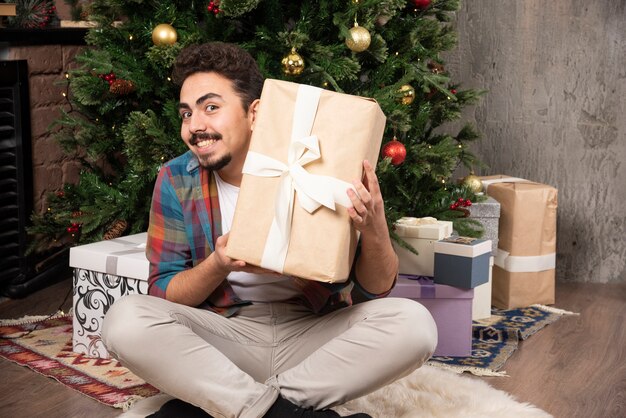 Uomo festivo che scuote il suo dono per ottenere quello che è.