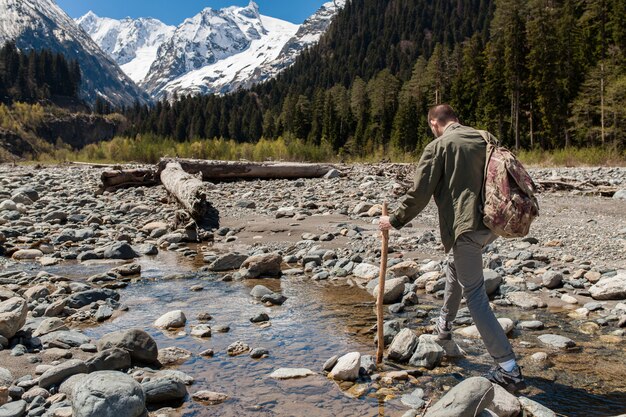 Uomo giovane hipster, escursioni al fiume nella foresta