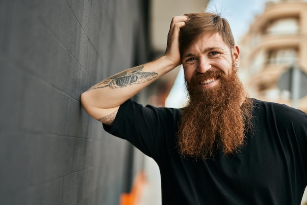 Uomo giovane hipster irlandese sorridente felice in piedi in città