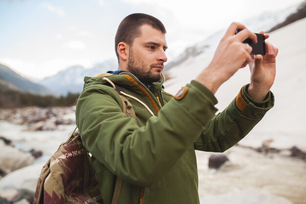 Uomo giovane hipster, scattare foto utilizzando smartphone, natura selvaggia, vacanze invernali, escursionismo