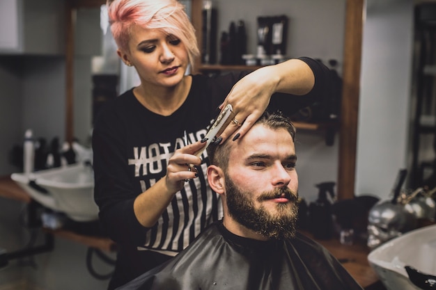 Uomo haircutting della donna in salone