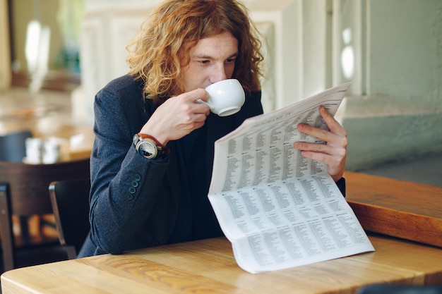 Uomo hipster che beve caffè durante la lettura