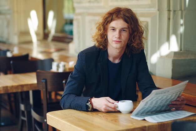 Uomo hipster che beve caffè durante la lettura