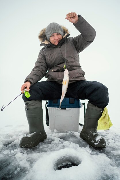 Uomo in abiti invernali che pesca da solo all'esterno