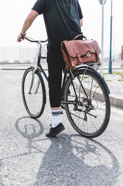 Uomo in abiti neri in sella alla bicicletta su strada