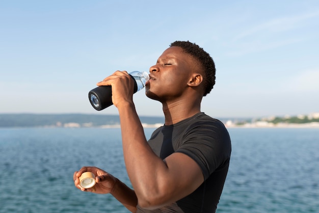 Uomo in abiti sportivi con in mano una bottiglia d'acqua