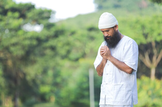 Uomo in abito bianco meditando nella natura