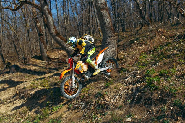 Uomo in attrezzatura sportiva in sella a una moto da cross in montagna