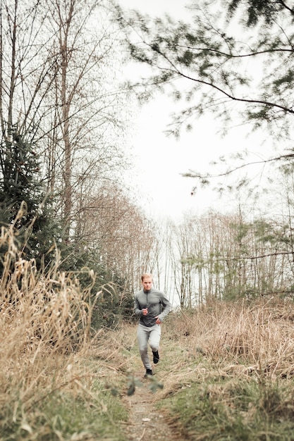 Uomo in buona salute di forma fisica che funziona sulla traccia della foresta