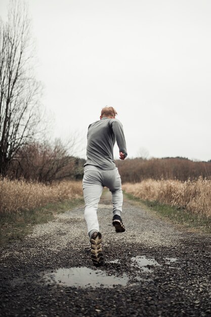 Uomo in buona salute di forma fisica che funziona sulla traccia della foresta