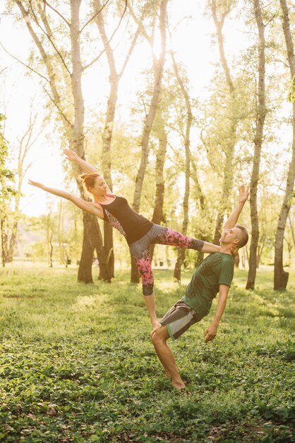 Uomo in buona salute e donna che fanno acroyoga in parco