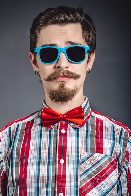 Uomo in camicia a quadri e farfallino con gli occhiali in studio