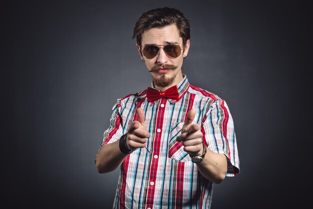 Uomo in camicia a quadri e farfallino con gli occhiali in studio