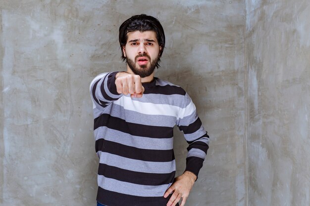 Uomo in camicia a righe che mostra il pugno