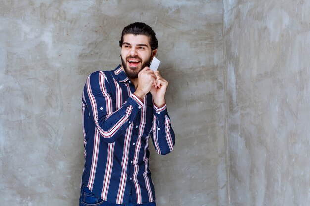 Uomo in camicia a righe che tiene il suo biglietto da visita