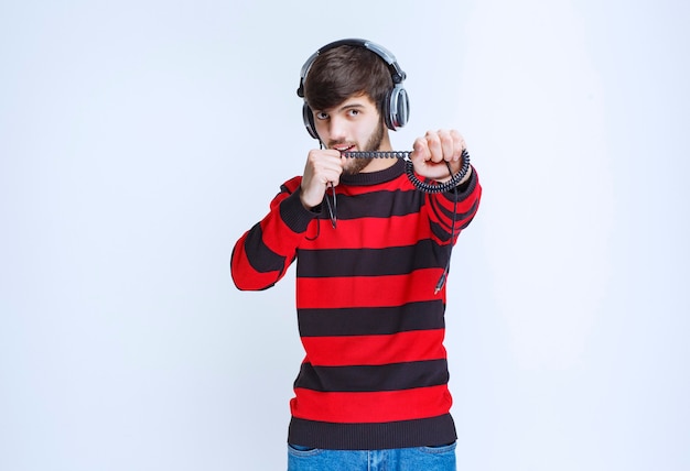 Uomo in camicia a righe rossa che ascolta le cuffie e imposta la musica dalla sua playlist sullo smartphone.