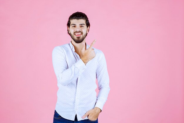 Uomo in camicia bianca che alza la mano per attirare l'attenzione o mostrare qualcosa.