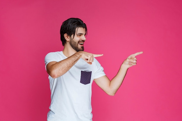 Uomo in camicia bianca che indica da qualche parte e presenta qualcuno o mostra semplicemente la direzione.