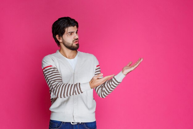 Uomo in camicia bianca che indica da qualche parte e presenta qualcuno o mostra semplicemente la direzione.