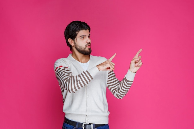 Uomo in camicia bianca che indica e che presenta qualcosa nella parte di destra.