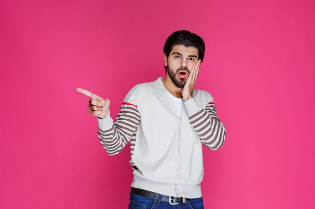 Uomo in camicia bianca che indica e che presenta qualcosa sul lato sinistro.