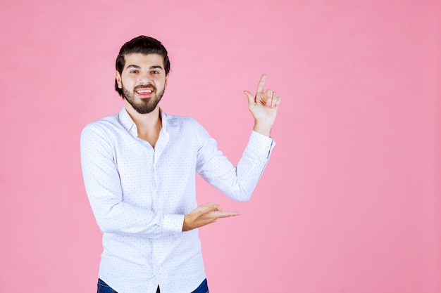 Uomo in camicia bianca che indica il lato destro.