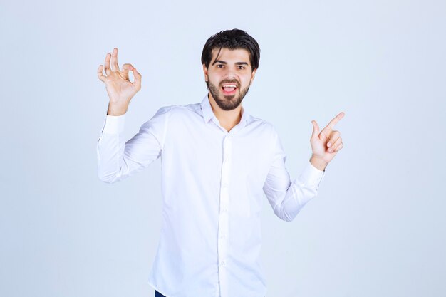 Uomo in camicia bianca che indica qualcosa sulla destra.