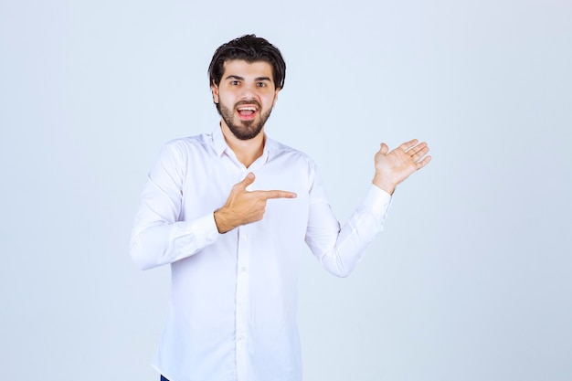 Uomo in camicia bianca che indica qualcosa sulla destra.