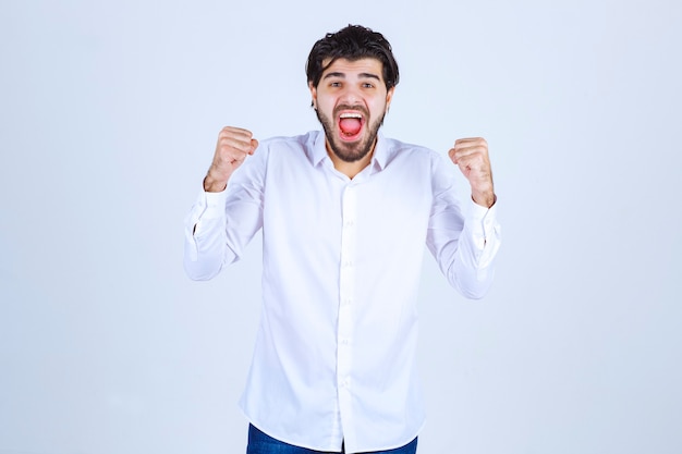 Uomo in camicia bianca che mostra i pugni e si sente di successo