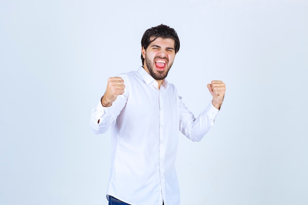 Uomo in camicia bianca che mostra i pugni e si sente di successo