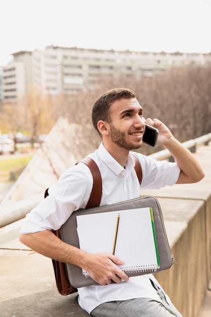 Uomo in camicia bianca che parla sul telefono e che guarda su