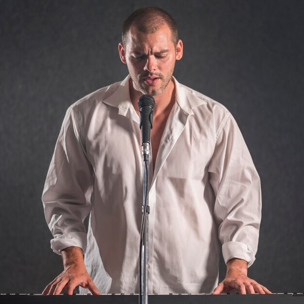 Uomo in camicia bianca che suona le tastiere e canta