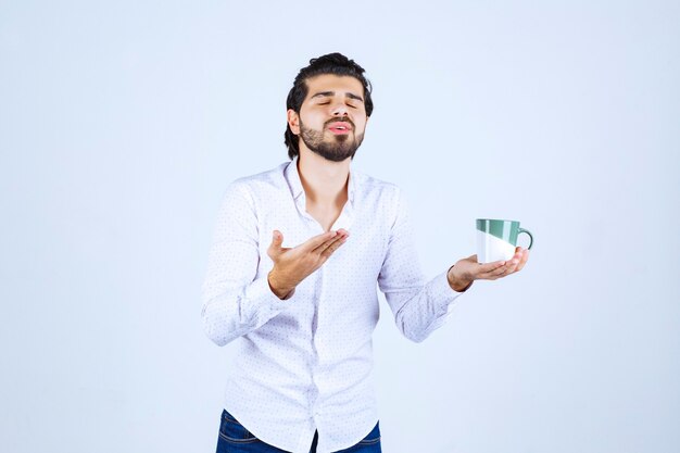 Uomo in camicia bianca che tiene una tazza di caffè e se lo gode.