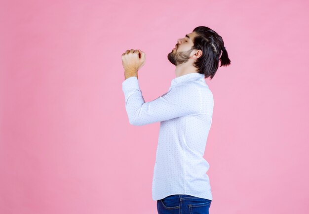 Uomo in camicia bianca che unisce le mani e prega.