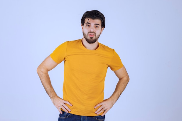 Uomo in camicia gialla che dà pose seducenti e attraenti