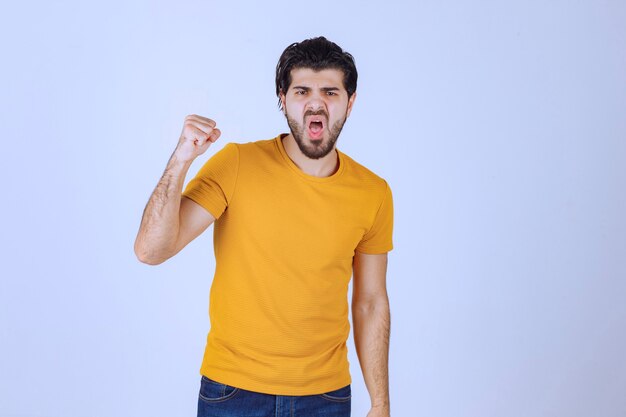 Uomo in camicia gialla che mostra il pugno e il potere.